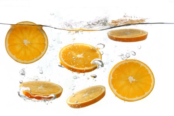 پرتقال های تکه تکه شده در حال ریختن در آب زلال