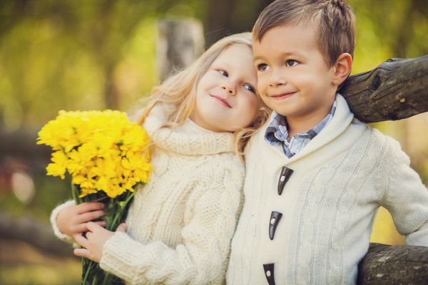 بچه های شاد شایان ستایش در فضای باز در روز آفتابی در باغ پاییزی زرد زیبا