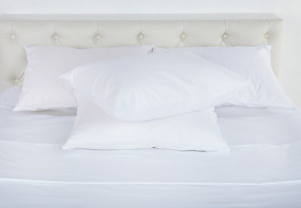 بالش های سفید روی تخت در اتاق