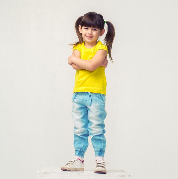 پرتره دختر کوچولوی ناز در استودیوی ایستاده تمام قد شلوار جین جدا شده روی سفید