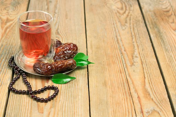 طبیعت بی جان غذا و نوشیدنی مفهوم تعطیلات خرما چای و مهره ماه رمضان روی میز چوبی فوکوس انتخابی پس‌زمینه فضای کپی