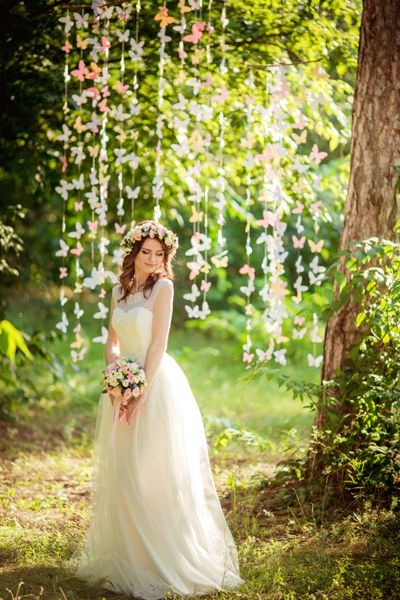 عروس زیبا با لباس سفید در باغ