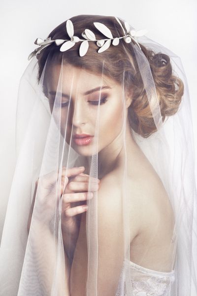 عروس زیبا با مدل موی عروسی مد - در پس زمینه سفید پرتره نزدیک از عروس جوان زرق و برق دار عروسی عکس استودیو پرتره عروس زیبا با حجاب روی صورتش