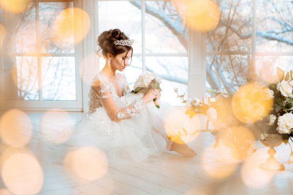 عروس عروسی عروس در یک لباس کوتاه با توری در گوشواره تاج دسته گل عروسی آرایش مدل مو سبک عروسی