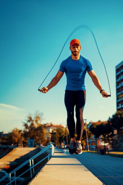 پرتره مرد جوان عضلانی در حال ورزش با طناب پریدن