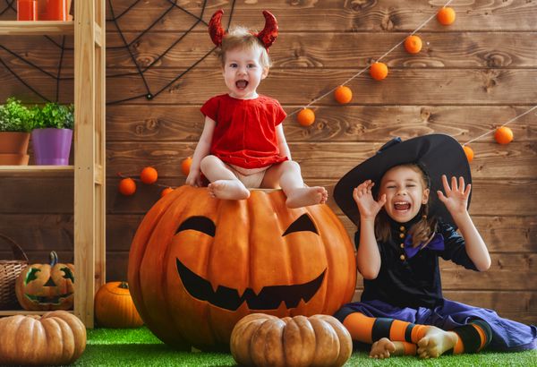 دو خواهر بامزه بامزه تعطیلات را جشن می گیرند کودکان شاد با لباس های کارناوال آماده برای هالووین