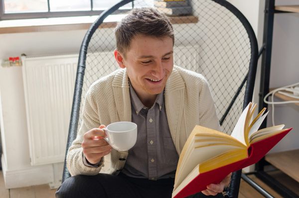 مرد در حال خواندن کتاب جالب و لبخند زدن است