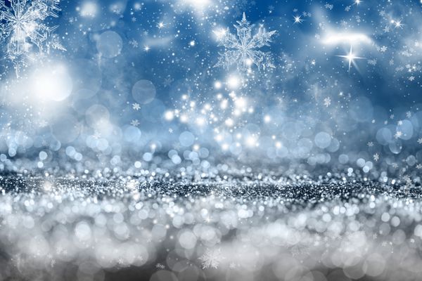 پس زمینه پر زرق و برق انتزاعی تعطیلات آبی جادویی با ستاره های چشمک زن و دانه های برف در حال سقوط بوکه تار از چراغ های کریسمس