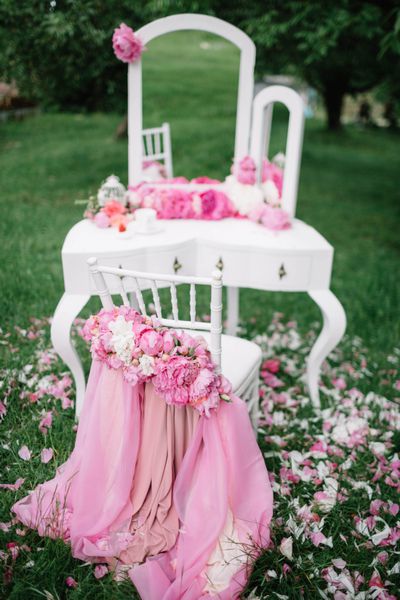 میز آرایش و صندلی سفید با تزئینات گلدار در فضای باز ایستاده است