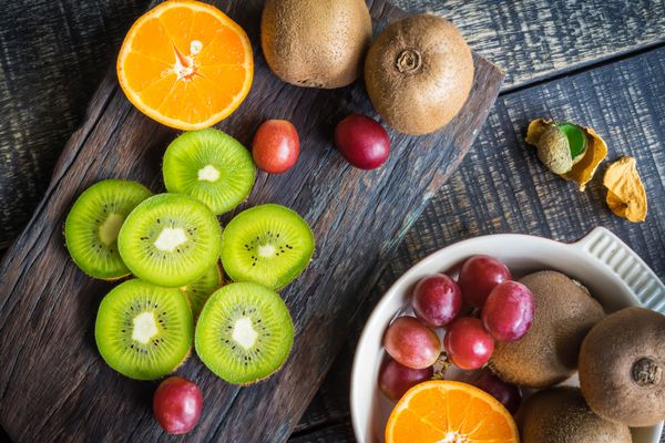ترکیبی از میوه های تازه برای سلامتی کیوی انگور قرمز و پرتقال در زمینه چوبی روستایی نمای بالا
