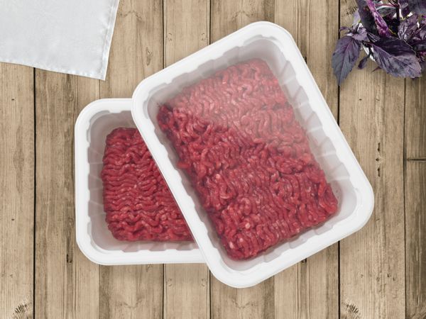 دو گوشت فورس در یک ظرف پلاستیکی سفید روی زمینه میز چوبی ماکت برای ارائه طرح بسته شما