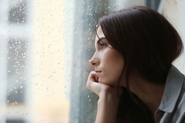 زن جوان افسرده نزدیک پنجره خانه نمای نزدیک