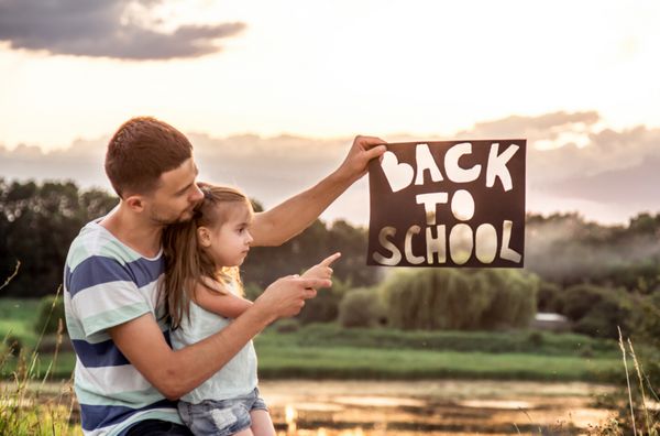 پدر شاد با دختر ناز که سخت در طبیعت کار می کند با پوستر در دست به مدرسه مفهوم آموزش ارزش های خانواده