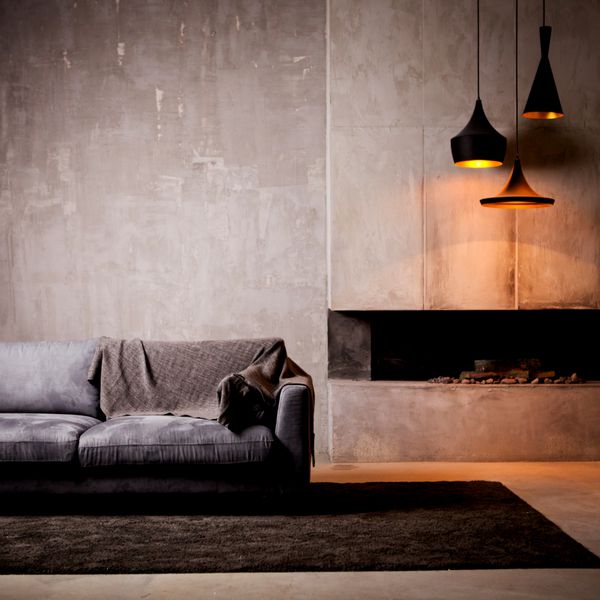 مبل مخمل خاکستری در یک اتاق تاریک نور روشن از نور ابدی و شومینه مصنوعی انبار داخلی با دیوارهای بتنی