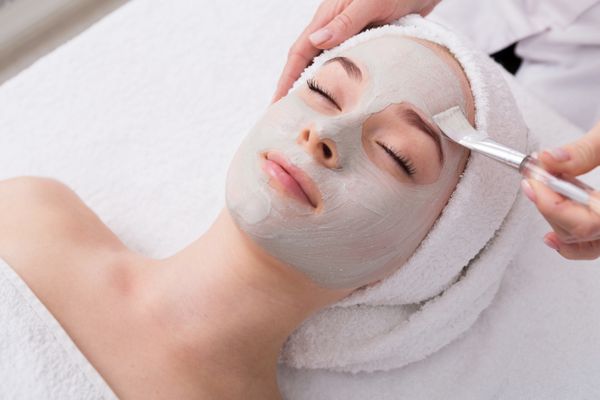 ماسک لایه بردار صورت درمان زیبایی اسپا مراقبت از پوست زنی که توسط آرایشگر در سالن آبگرم مراقبت از صورت نمای جانبی نمای نزدیک