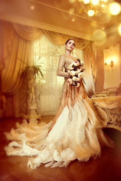 زن زیبا و زیبا با لباس شب زیبا در اتاق داخلی به سبک مجلل پرتره خانم شیک تمام قد با لباس طلایی