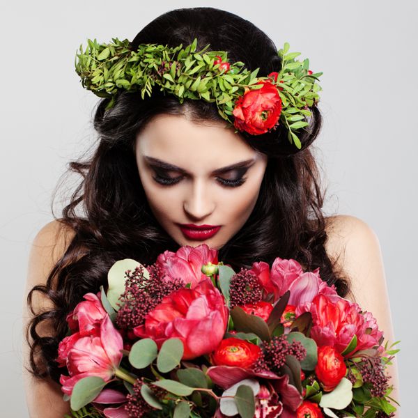 زن زیبا که گلهای تابستانی را در دست دارد