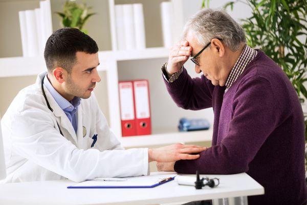 دکتر در حال گوش دادن به بیمار در حال توضیح دردناک خود است