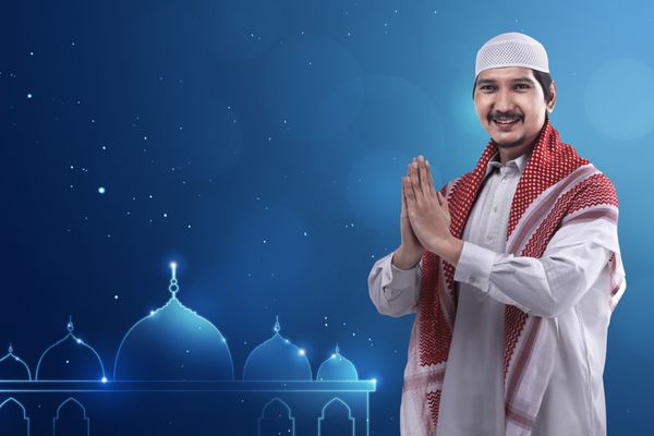 مرد جوان مسلمان آسیایی با کلاه و لباس تمیز و پس زمینه آرم مسجد