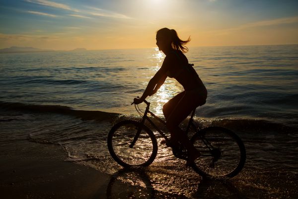 زن در تعطیلات دوچرخه سواری در ساحل