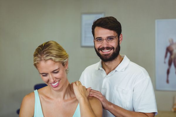 فیزیوتراپ مرد به بیمار زن گردن را ماساژ می دهد