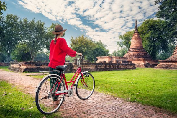 زنی با دوچرخه در نزدیکی خرابه های بودایی