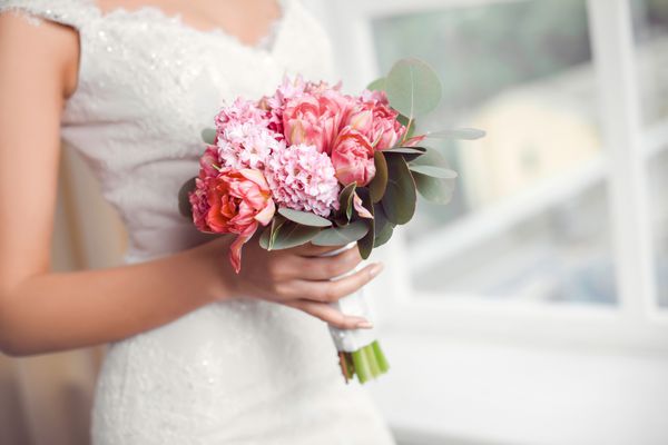 دسته گل عروس زیبا از گل های صورتی عروسی در دستان عروس