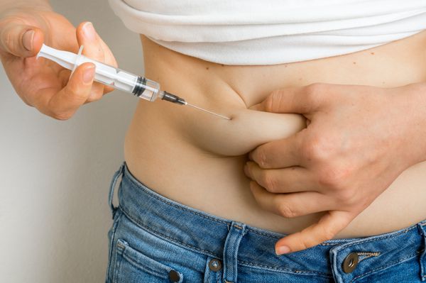 زن دیابتی با سرنگ انسولین را به شکمش تزریق می کند