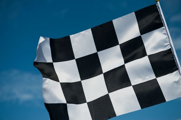 پرچم شطرنجی مسابقه روی آسمان آبی تکان می خورد