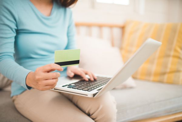 مفهوم خرید آنلاین زن جوان آسیایی که کارت اعتباری در دست دارد و از رایانه لپ‌تاپ استفاده می‌کند