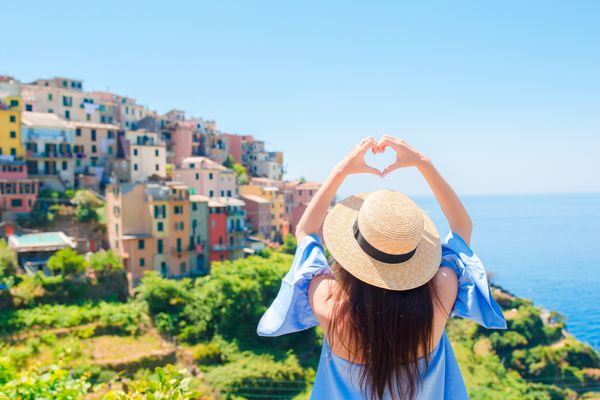 دختر شادی که با دستانش شکل قلب در دهکده ساحلی قدیمی در پارک ملی Cinque Terre می سازد تعطیلات اروپایی