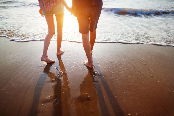 زوج جوان در حال قدم زدن در ساحل
