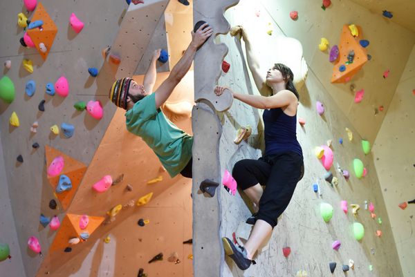 Junge Frau und Mann klettern bouldern در einer Kletterhalle در حال صعود در فضای داخلی