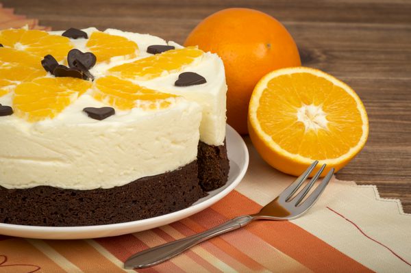 کیک براونی با خامه و پرتقال روی زمینه چوبی