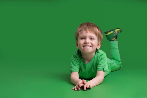 پسر در لباس سبز نما در دوربین با پس زمینه سبز