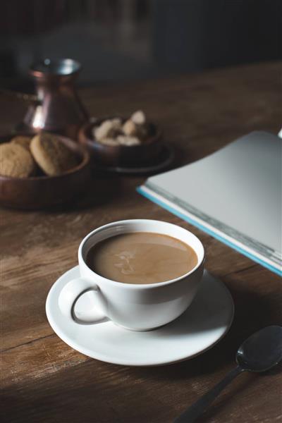فنجان قهوه با کتاب خالی روی میز