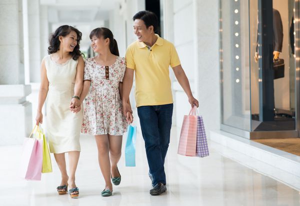 تصویر کامل از راه رفتن خانواده شاد در مرکز خرید با هم