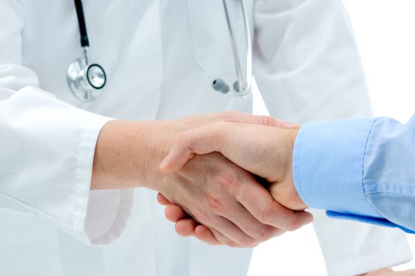 دکتر دست ها را با یک بیمار جدا شده بر روی زمینه سفید لرزاند