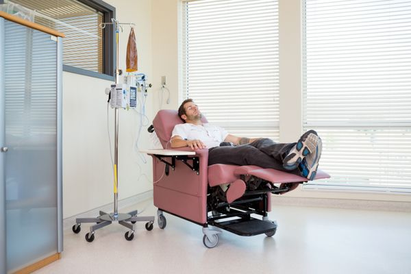 طول کامل بیمار مردی که در طول شیمیدرمانی در اتاق بیمار آرامش می یابد