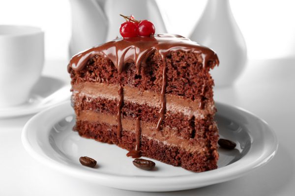 کیک شکلاتی خوشمزه بر روی میز در پس زمینه نور