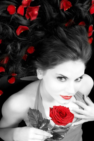زاویه دید گسترده ای از زن زیبا با لباس قرمز گل رز و گلبرگ