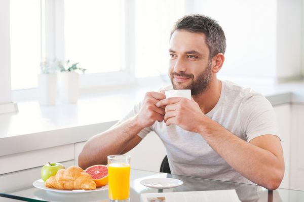 شروع روز با تازه و قهوه خوشبختانه مرد جوان لذت بردن از قهوه تازه در هنگام نشستن در آشپزخانه
