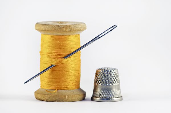 Old spool of thread with needle closeup Tailor