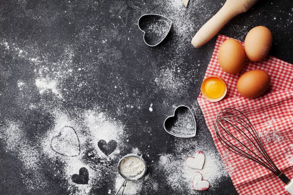 پس زمینه پخت با آرد نورد پین تخم مرغ و شکل قلب در جدول آشپزخانه تاریک نمایش بالا برای پخت و پز روز ولنتاین سبک تختخواب