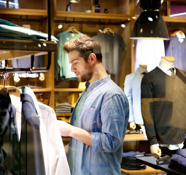 پرتره یک مرد جوان خوش تیپ برای خرید لباس در مغازه