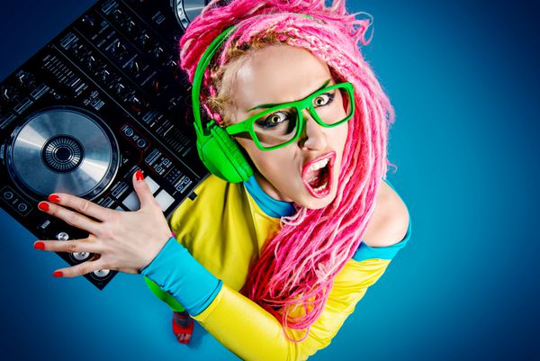 دختر برجسته DJ مدرن با پوشیدن لباس های روشن هدفون و dreadlocks درخشان برخی از موسیقی را مخلوط می کند دیسکو مهمانی نسل جدید