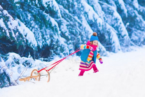 دختر کوچک با بهره گیری از یک سورتمه سواری کامیون کودکان کودک نوپا بچه سواری کودکان در خارج از منزل در برف بازی می کنند کودکان و نوجوانان در کوه های آلپ در زمستان سرگرمی در فضای باز برای تعطیلات کریسمس خانواده