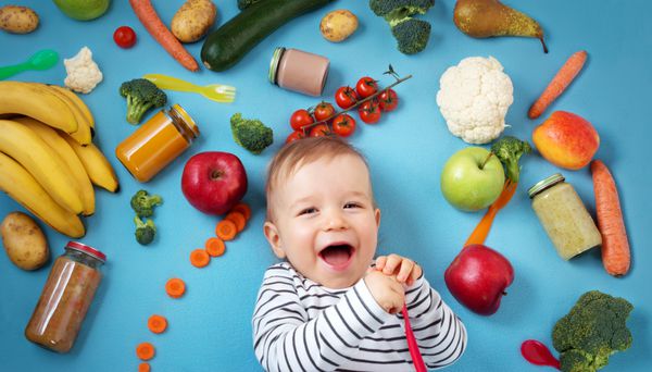 کودک با میوه ها و سبزیجات بر روی پتو آبی تغذیه سالم بچه ها احاطه شده است