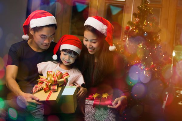 خانواده آسیایی در روز کریسمس یک جعبه هدیه را می کنند