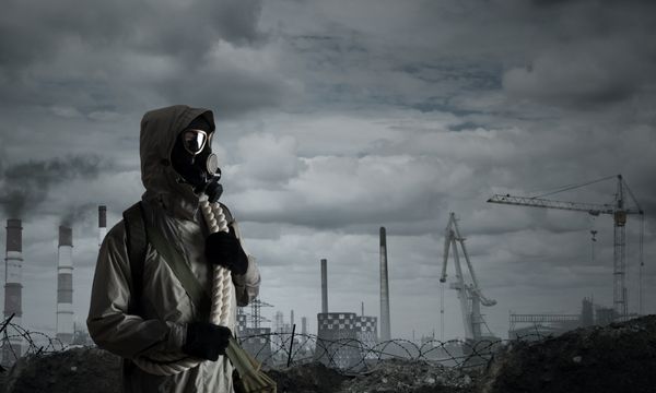 انسان بازمانده در ماسک گاز در پس زمینه خاکستری صنعتی